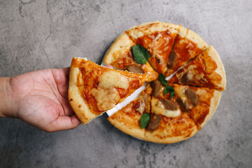Top View Of Hand Taking Pepperoni Pizza Slice Over Grey Background