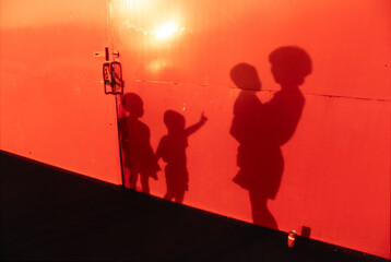 港の倉庫の壁にシルエットになって映し出された親子の影