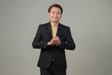 portrait of happy asian businessman wearing suit clapping hand on isolated background.