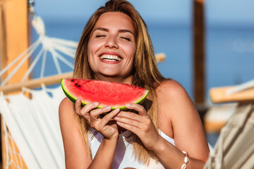 Young beautiful woman eating juicy watermelon on the beach.