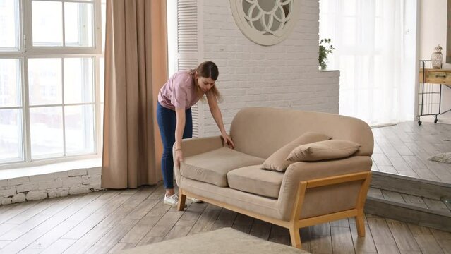 A woman has lost something in the room and is trying to search the sofa. She is looking for keys or phone