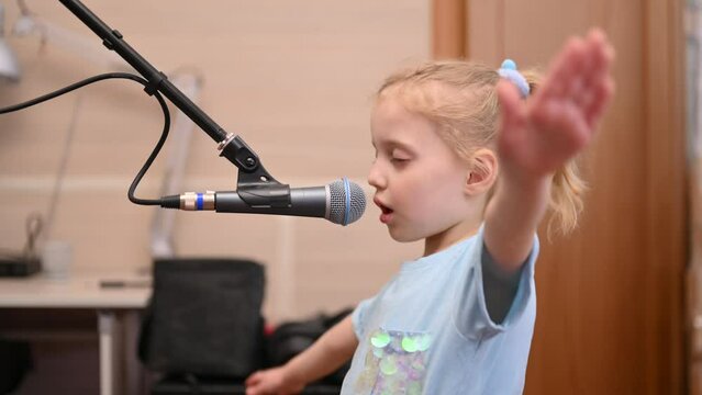 Little girl enjoying singing into a microphone. Close up