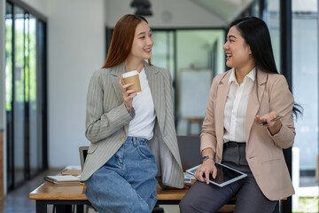 Fototapeta premium Two Asian businesswomen working Creative discussion in office using laptop and tablet, business concept