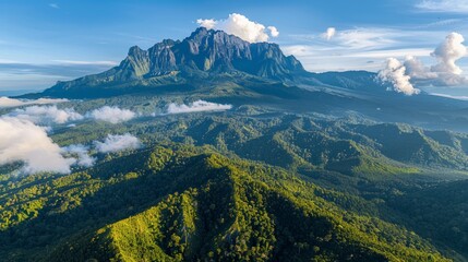 Aerial view of Mount Kinabalu in Malaysia, showcasing its rugged peak and surrounding lush rainforest, with distant views of the South China Sea.     