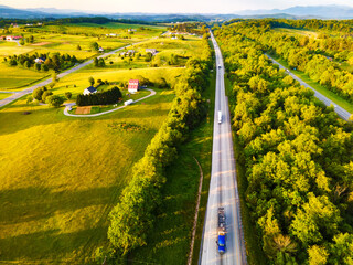 Top view from a drone of a road among forests and meadows.