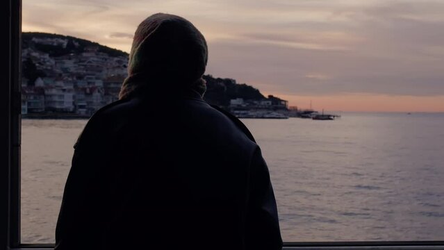 Silhouette of muslim woman in hijab looking seascapefrom ferry, cinematic color