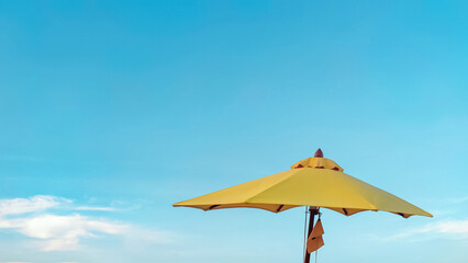 Yellow parasol against bright blue sky background. Summer vacation. Beach umbrella.