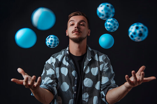 Man juggling blue balls on black background. Stylish Man with black and white shirt posing for the camera
