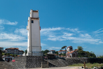 Farol à beira-mar para orientação da navegação marítima com parte da cidade turística de...
