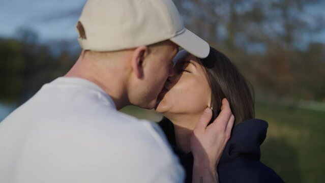 Lovely couple at park, guy gently touch cheek and kiss girlfriend on lips