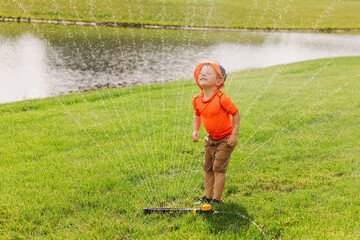 Young child enjoying water play in sprinkler on grass