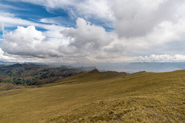 a mountain range with yellow grass and cloudy sky - Powered by Adobe