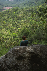 Man looks at the valley from the top of the mountain.