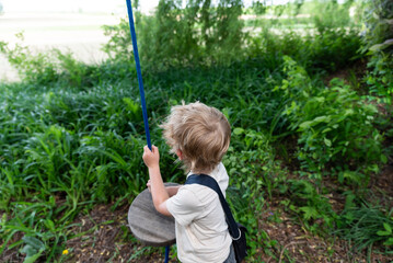 Young Boy on rope swing playing in nature