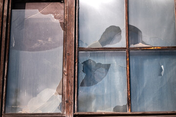 Detail of an old window with frames and broken glass in daylight