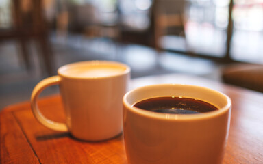 Two white cups of hot coffee on wooden table in cafe