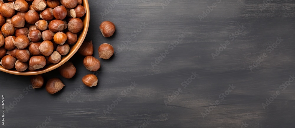 Aufkleber Top view of a bowl filled with hazelnuts on a grey background providing copy space for the image