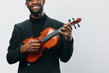 Elegant African American man in black suit holding violin against white background, isolated image