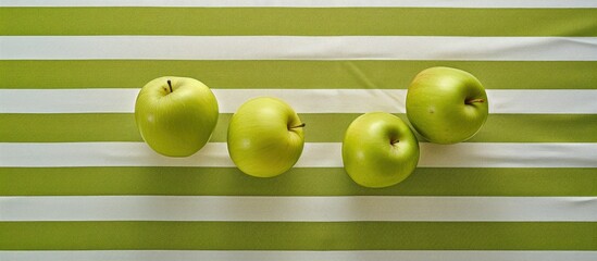 The table is adorned with three green apples on a striped tablecloth The view from above offers a clear space for potential use. Creative banner. Copyspace image