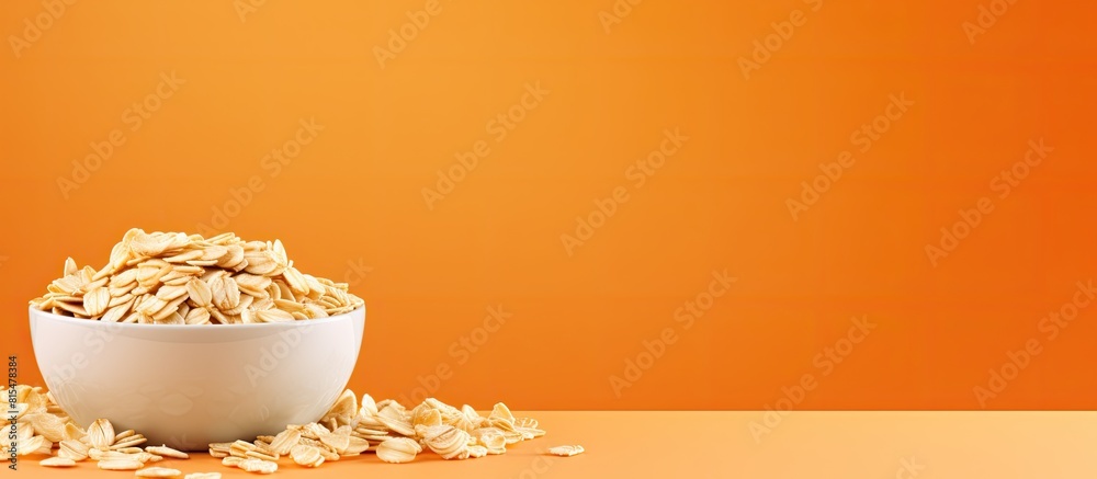 Poster copy space image of a bowl filled with uncooked oatmeal flakes placed on a vibrant orange background