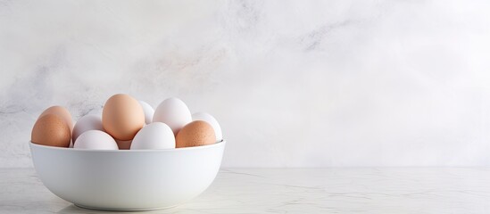 A copy space image featuring a bowl of white eggs placed on a pristine white granite countertop
