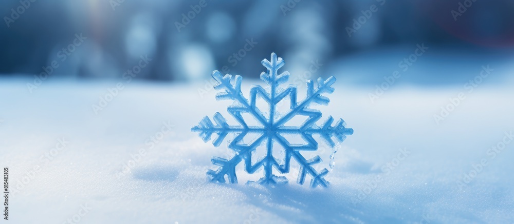 Fototapete A snowflake with a blue hue stands out against the white snow on a snowy background creating a visually striking image with plenty of copy space