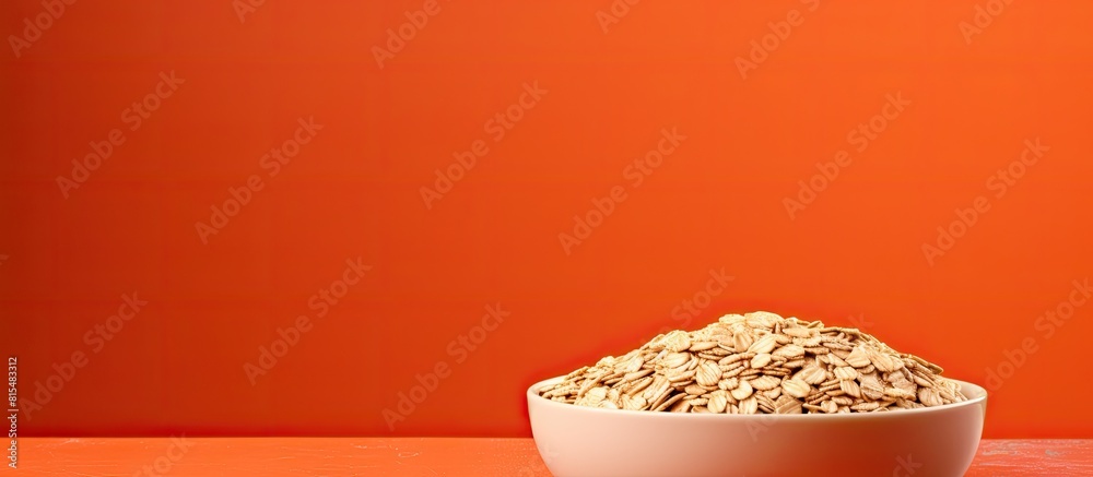 Poster copy space image of a bowl filled with uncooked oatmeal flakes placed on a vibrant orange background