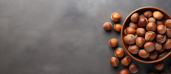 Top view of a bowl filled with hazelnuts on a grey background providing copy space for the image