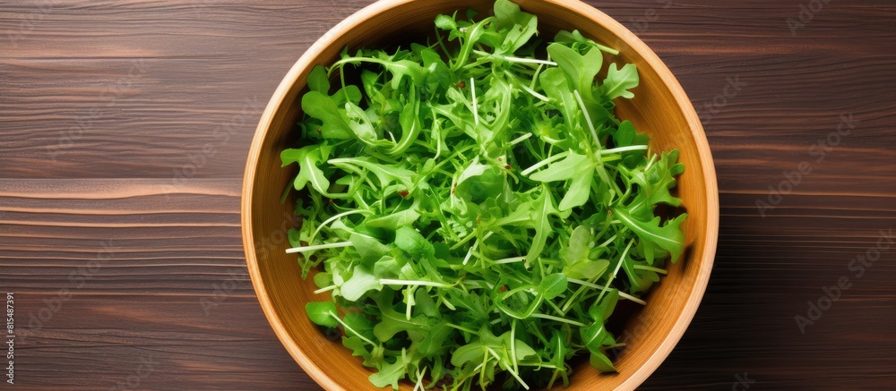 Poster a top down view of a wooden background featuring a bowl of fresh rucola salad with available copy sp