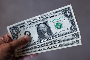 Hand holding three one US Dollar banknotes