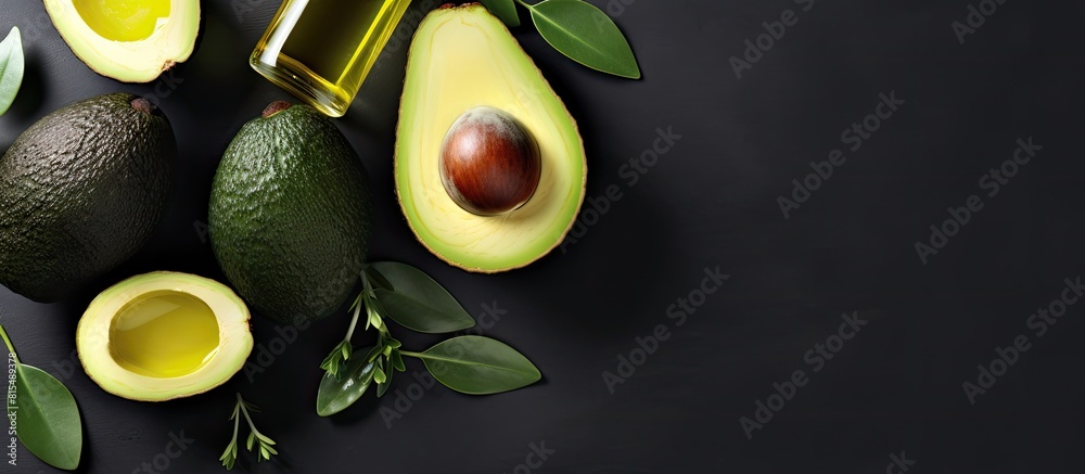 Poster top view copy space image of bottles containing avocado oil alongside slices of avocado on a grey ba
