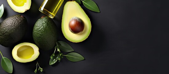 Top view copy space image of bottles containing avocado oil alongside slices of avocado on a grey background showcasing natural skin care products
