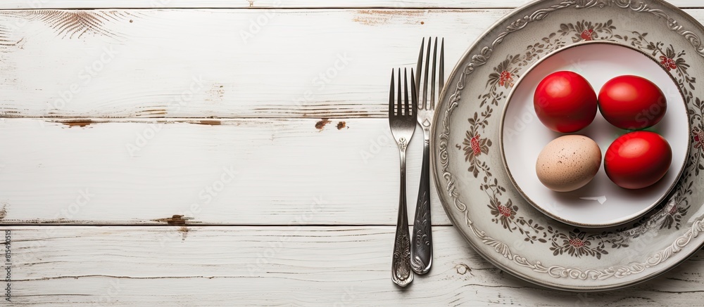 Poster A top down view of a plate with vintage silverware and red Easter eggs on a white shabby wooden table creating a visually appealing copy space image