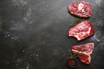 Raw organic marbled beef steaks : ossobuko, rib eye ( cowboy ) , T - bone. Top view with copy space.