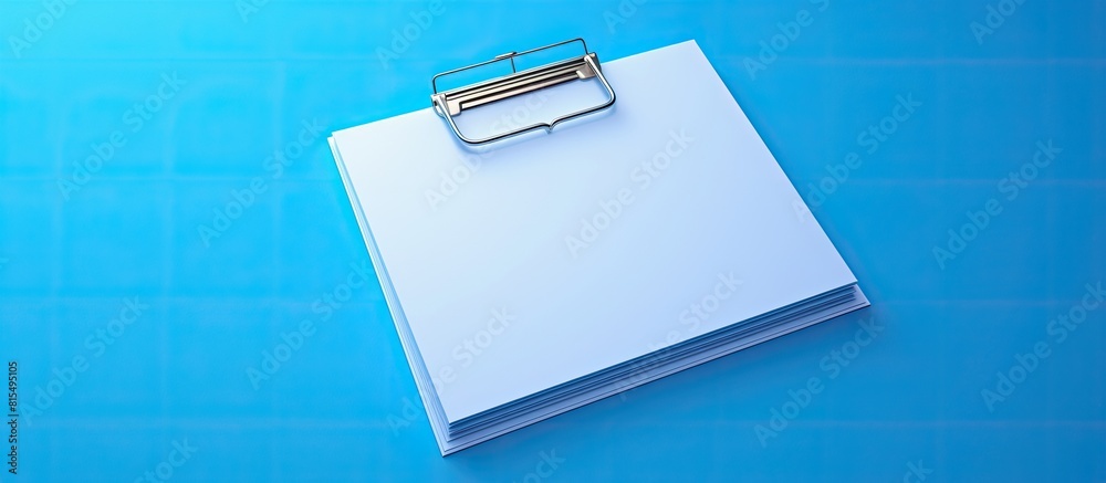 Fototapete isolated on a blue background there is a white paper note held in place by a paper clip the image of