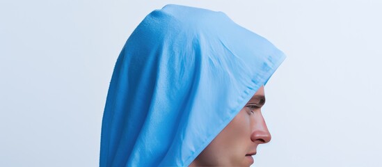 A man wearing a blue towel on his head stands alone against a white background in the copy space image