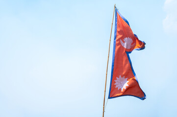 The national flag of Nepal against sky. The shape of the flag is said to represent the Nepalese...