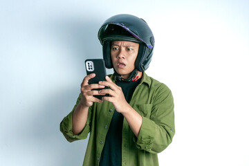 Adult Asian man confusing when looking to his handphone while wearing motorcycle helmet. Man looking to his phone with shocked expression