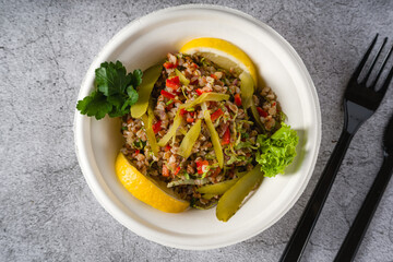 Quinoa salad on a white styrofoam plate on a stone table