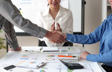 Businessmen shake hands to end the meeting. Successful negotiations and handshakes Group of business people congratulating each other inside the office.