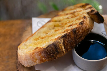 Traditional sourdough bread, sliced on a wooden board with olive oil and balsamic vinegar dipping...