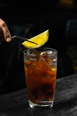 Garnishing espresso tonic cold coffee drink with a lemon wedge