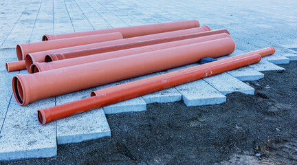 Side view of plastic orange pipes at a construction site