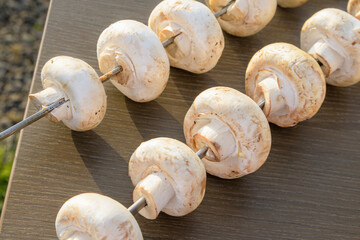 Large porcini mushrooms are skewered for grilling. Close-up
