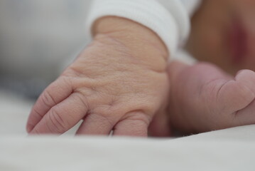 A close-up of a newborn's hand , showing the delicate skin and tiny fingers and toes. The baby is...