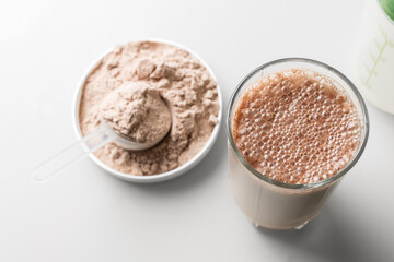 Protein drink cocktail in a glass and whey protein powder in a measuring scoop