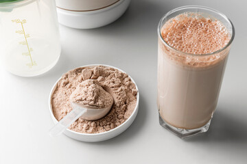 Protein drink cocktail in a glass and whey protein powder in a measuring scoop