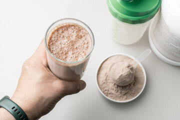 Male hand holding a protein drink cocktail in a glass