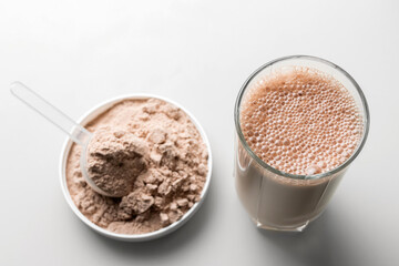 Protein drink cocktail in a glass and whey protein powder in a measuring scoop