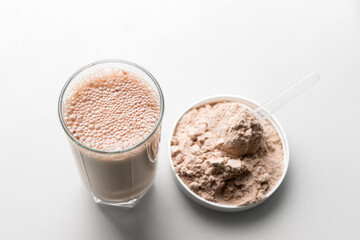 Protein drink cocktail in a glass and whey protein powder in a measuring scoop